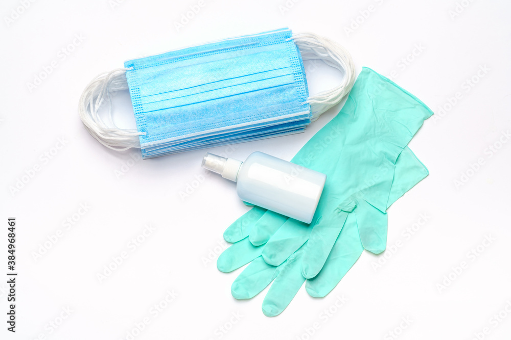 Disposable blue medical face mask, rubber latex gloves and alcohol hand sanitizer antiseptic on light grey background Disposable blue medical face mask, rubber latex gloves and alcohol hand sanitizer antiseptic on light grey background
