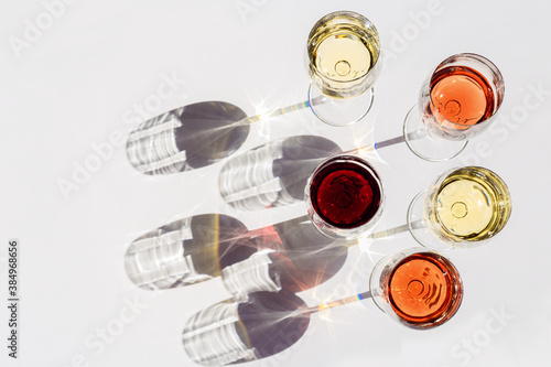 Red, rose and white wine top view in sunlight. Assorted wine in glass on white table. Dark shadows.