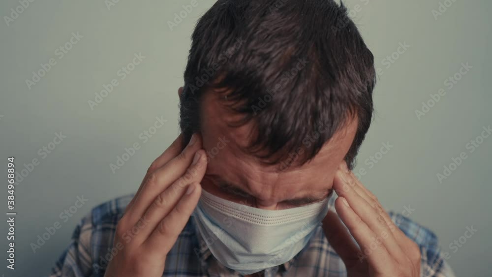 man wear puts on protective mask sick man feels pain in the head stress state a indoor portrait. epidemic corona outbreak concept. adult male face of sad tired in blue medical mask isolated man wear puts on protective mask sick man feels pain in the head stress state a indoor portrait. epidemic corona outbreak concept. adult male face of sad tired in blue medical mask isolated