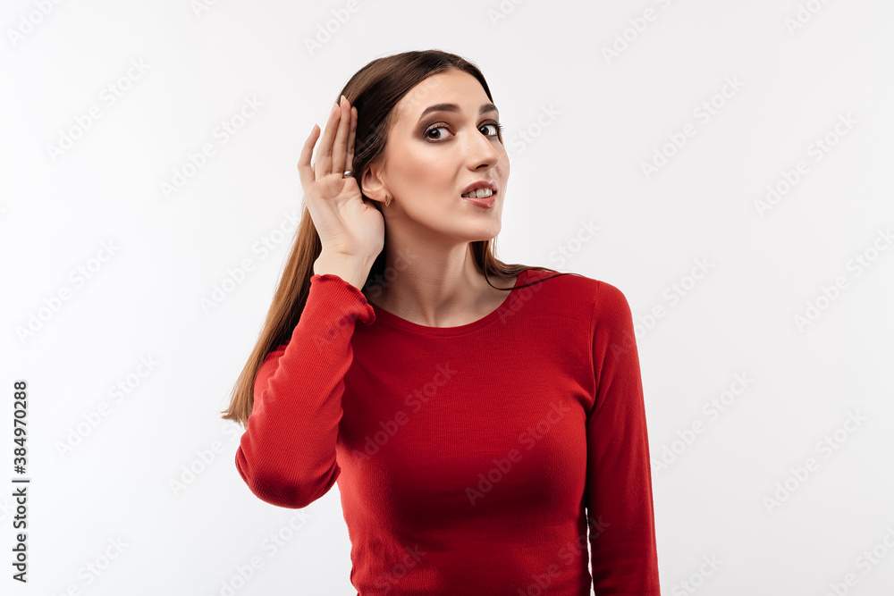 Young pretty brunette woman holding hand near ear trying to listen something. Human emotions, facial expression concept Young pretty brunette woman holding hand near ear trying to listen something. Human emotions, facial expression concept