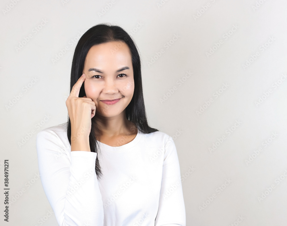 Asian woman wearing white t-shirt ,thinking , got idea, pointing fingers on her head, smiling and looking at camera. Asian woman wearing white t-shirt ,thinking , got idea, pointing fingers on her head, smiling and looking at camera.