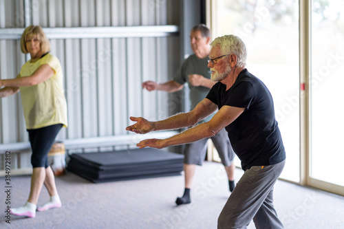 Group of elderly senior people practicing Tai chi class in age care gym facilities.