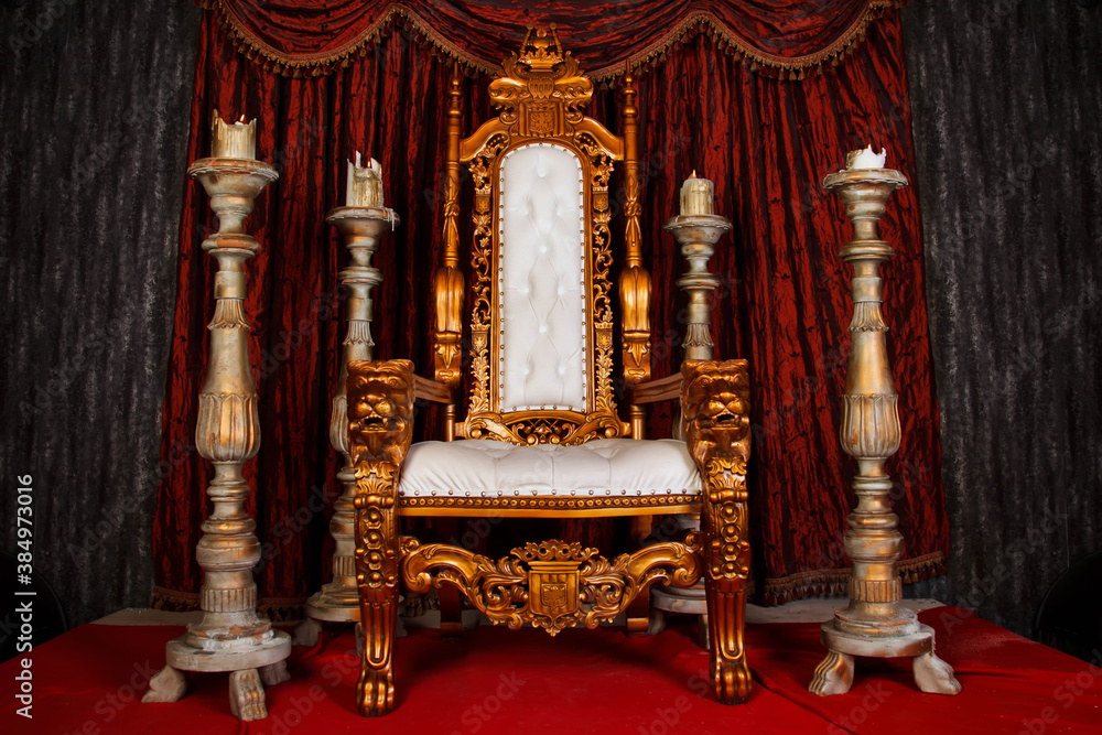 Old white and gold Royal chair with red curtains and candelabra in medieval  vintage room. Throne for king in castle. Background in architecture or retro  interior design. Copy space, text place Stock