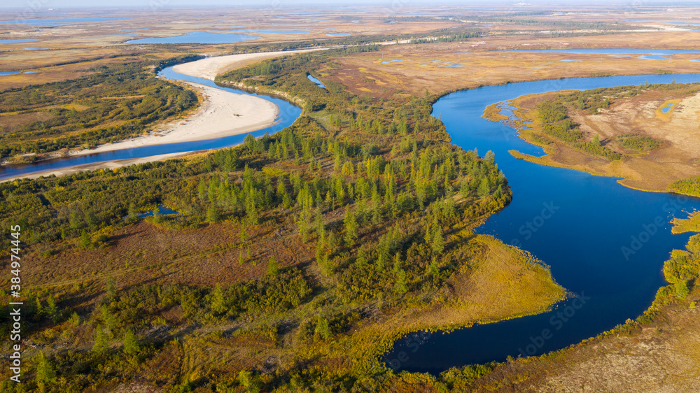 Landscape of the forest-tundra in autumn and the sandy river bank, bird's eye view.Arctic Circle, tunda. Beautiful landscape of  tundra from a helicopter.