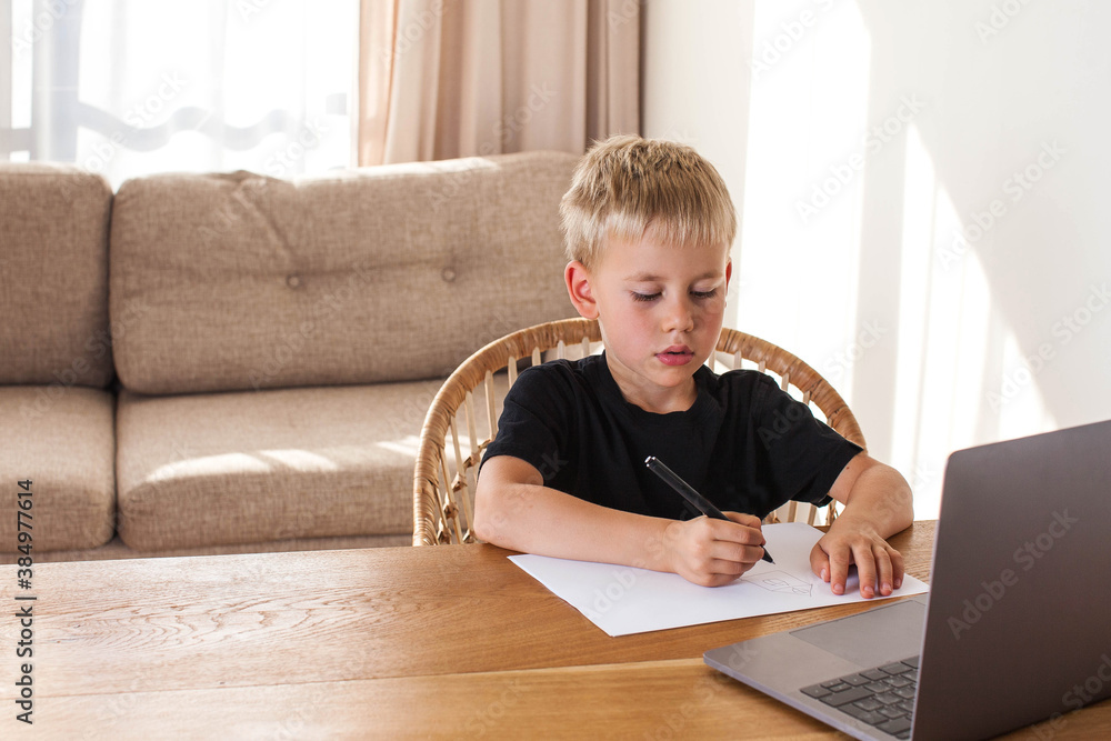 A blond boy draws from an online lesson. Distance learning. Copy space. A blond boy draws from an online lesson. Distance learning. Copy space.