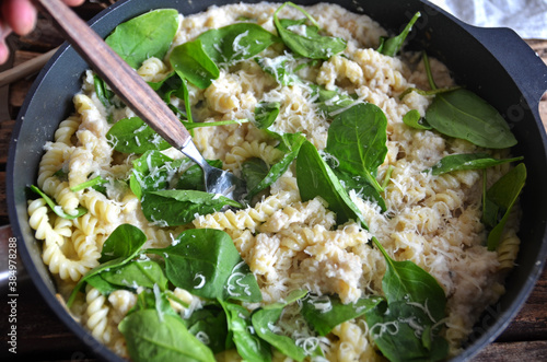 Spiral pasta with spinach leaves in a pan photo