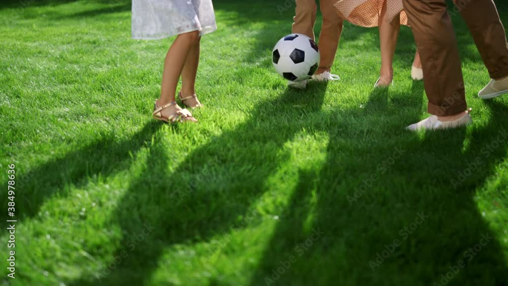 Closeup of parents and kids feet playing with soccer ball in green park Closeup of parents and kids feet playing with soccer ball in green park