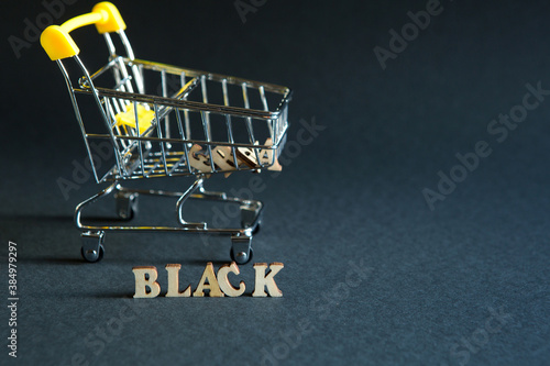 Shopping cart and the inscription "black" on a black background. Black Friday, discounts, sale, shopping, interest sign. Space for text