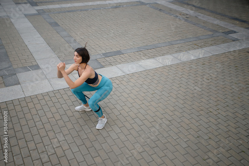 Full length of a sportswoman doing stretching exercise by a wall outdoors. Fitness woman exercising by a wall. free time, spare time, leisure