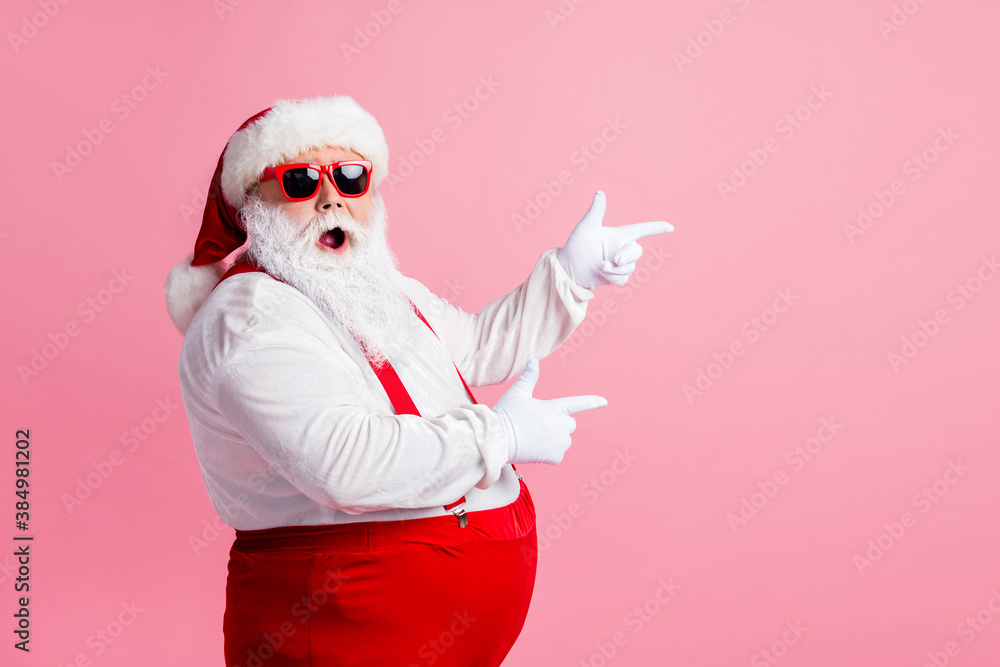 Profile side photo of astonished santa claus point index finger copyspace x-mas ads wear sunglass headwear suspenders headwear isolated over pastel color background - obrazy, fototapety, plakaty 