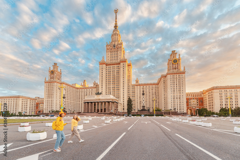 Obraz premium Two female friends students on the background of the building of Moscow University. Education, tourism and holiday concept