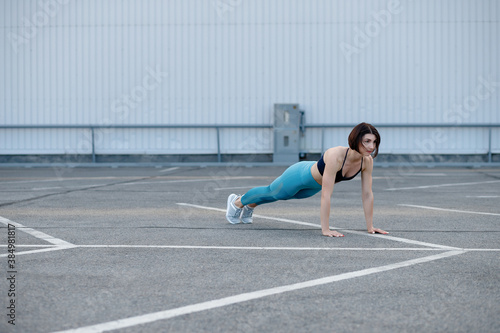 Young muscular woman doing core exercise. Fit female doing press-ups during the training outdoors.