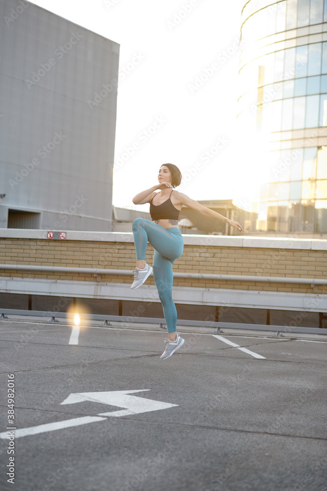 Full length image of fitness girl 20s in sportswear working out and running along wall