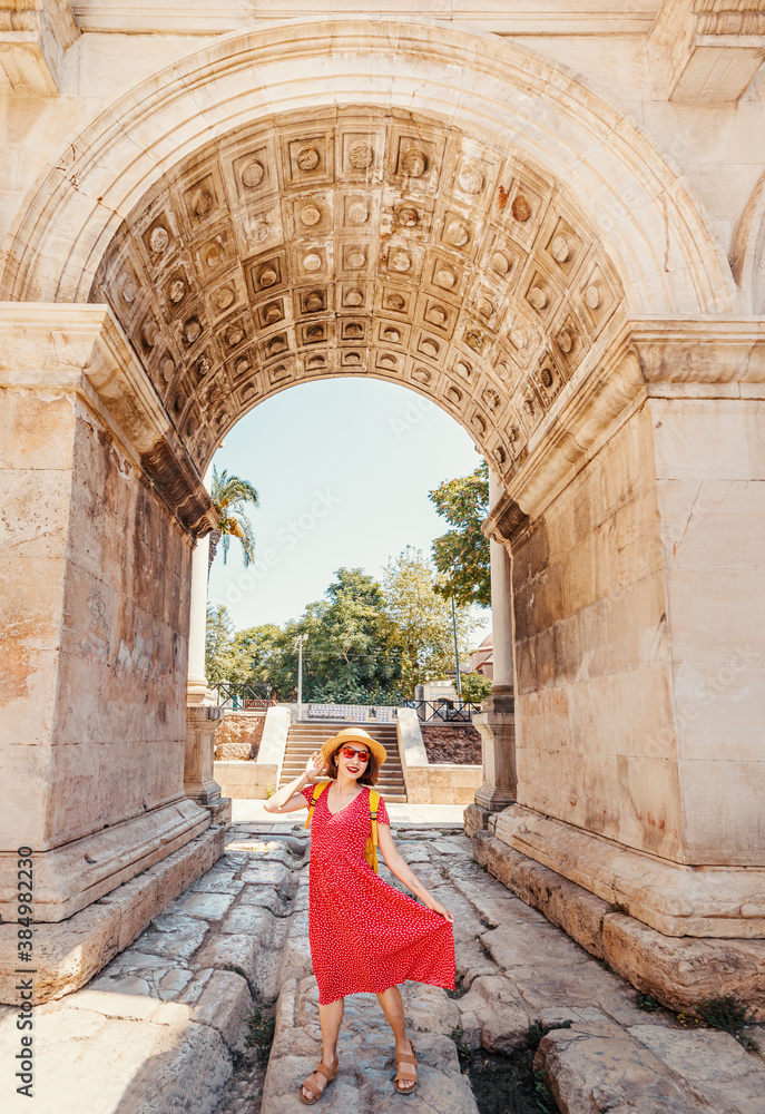 Happy female tourist traveler discover interesting places and popular attractions and walks in the old city of Antalya, Turkey. The famous Roman gate of Hadrian