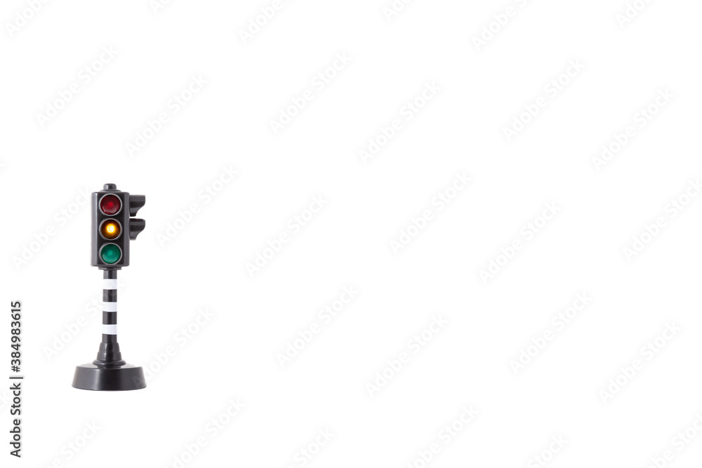 toy traffic light with orange light lit on white background toy traffic light with orange light lit on white background