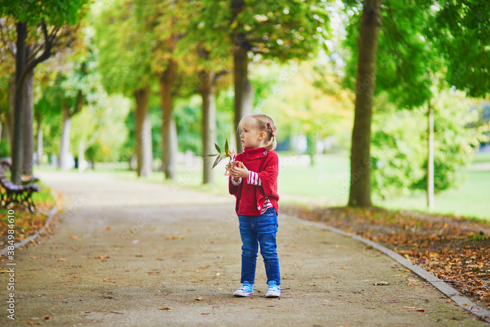 Adorable toddler girl playing in autumn park Adorable toddler girl playing in autumn park