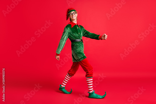 Full length profile side photo of positive elf guy go copyspace isolated over red bright color background