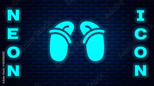 Glowing neon Flip flops icon isolated on brick wall background. Beach slippers sign. Vector.