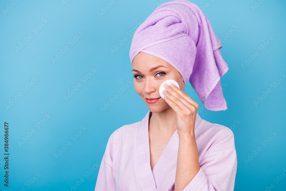 Photo of charming woman hand hold white sponge cheekbone wear violet towel turban bath robe isolated blue color background Photo of charming woman hand hold white sponge cheekbone wear violet towel turban bath robe isolated blue color background