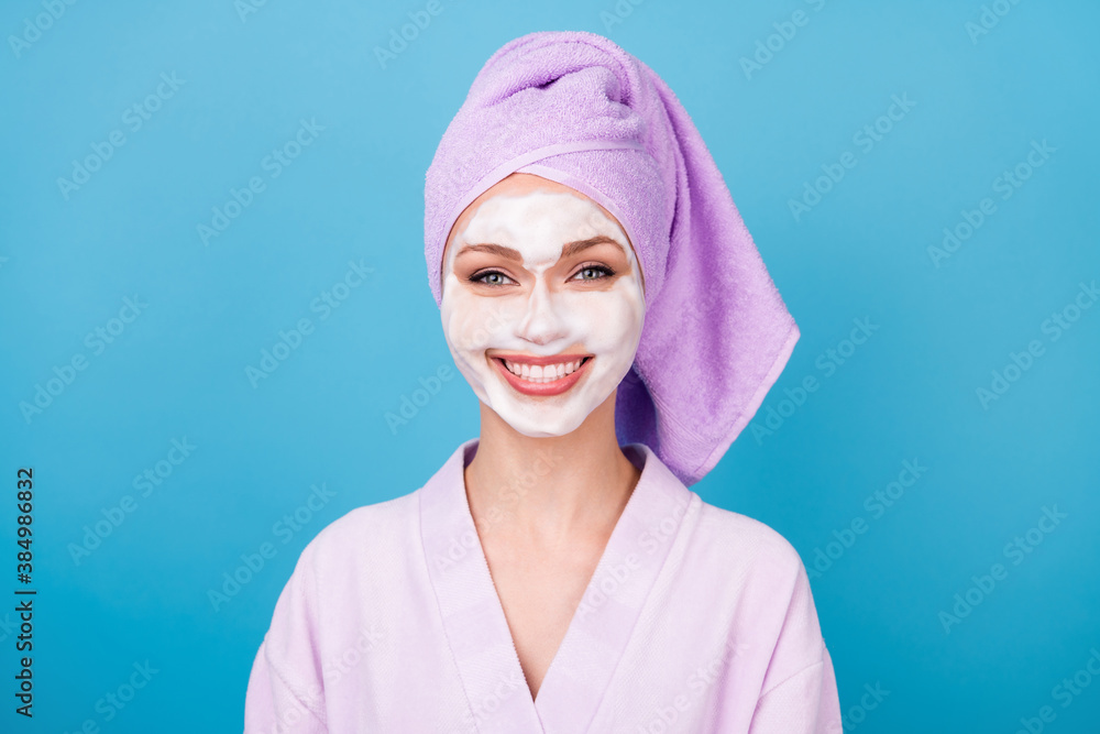 Photo of pretty girl facial foam mask shiny white smile wear violet towel turban bathrobe isolated blue color background Photo of pretty girl facial foam mask shiny white smile wear violet towel turban bathrobe isolated blue color background