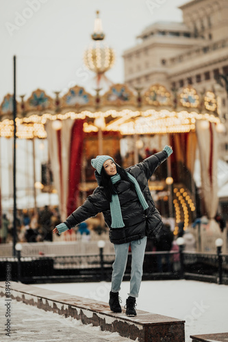 Girl walking in the amusement park near carousel in winter snowy day. 