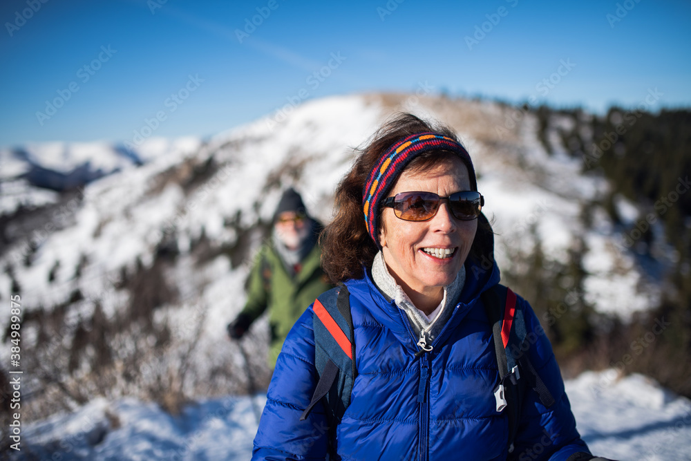 Senior woman with husband hiking in snow-covered winter nature.