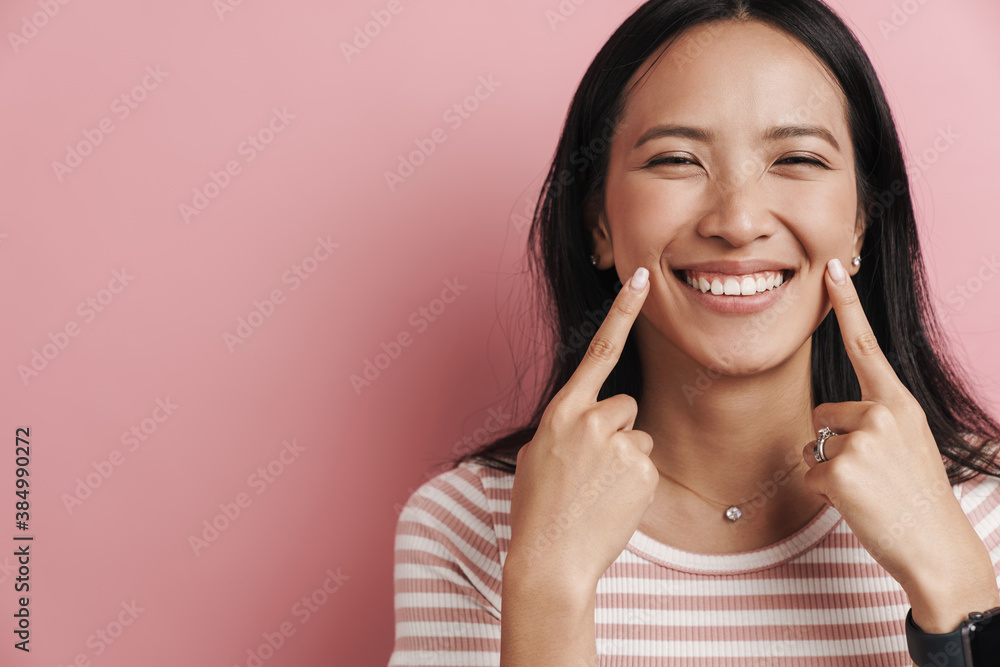 Beautiful joyful asian woman laughing and pointing fingers at her cheeks Beautiful joyful asian woman laughing and pointing fingers at her cheeks