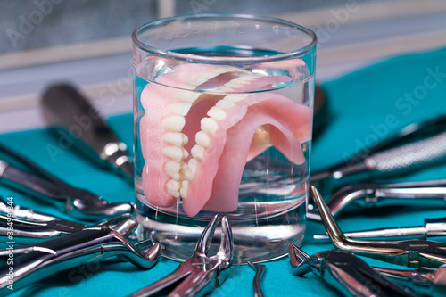Artificial teeth in a cup with dental  instruments photo