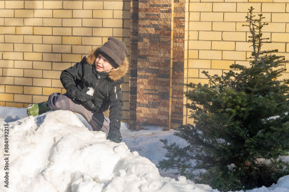 A cheerful, happy boy is playing in the wet spring snow. A European child throws a ball of snow at a friend. A cheerful, happy boy is playing in the wet spring snow. A European child throws a ball of snow at a friend.