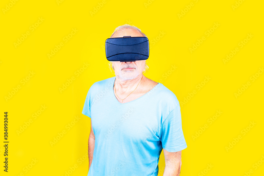 Eldelry man on yellow background using vr glasses - Isolated caucasian old man wearing futuristic headset astonished
