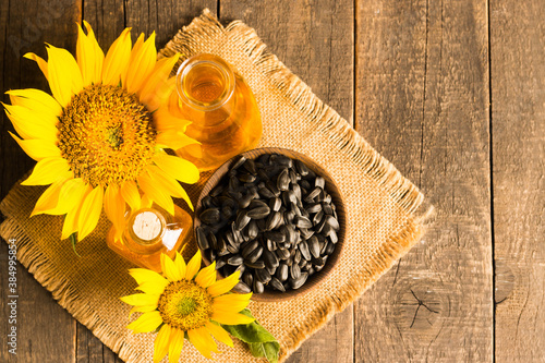 Closeup photo of sunflower oil with seeds on wooden background. Bio and organic product concept.