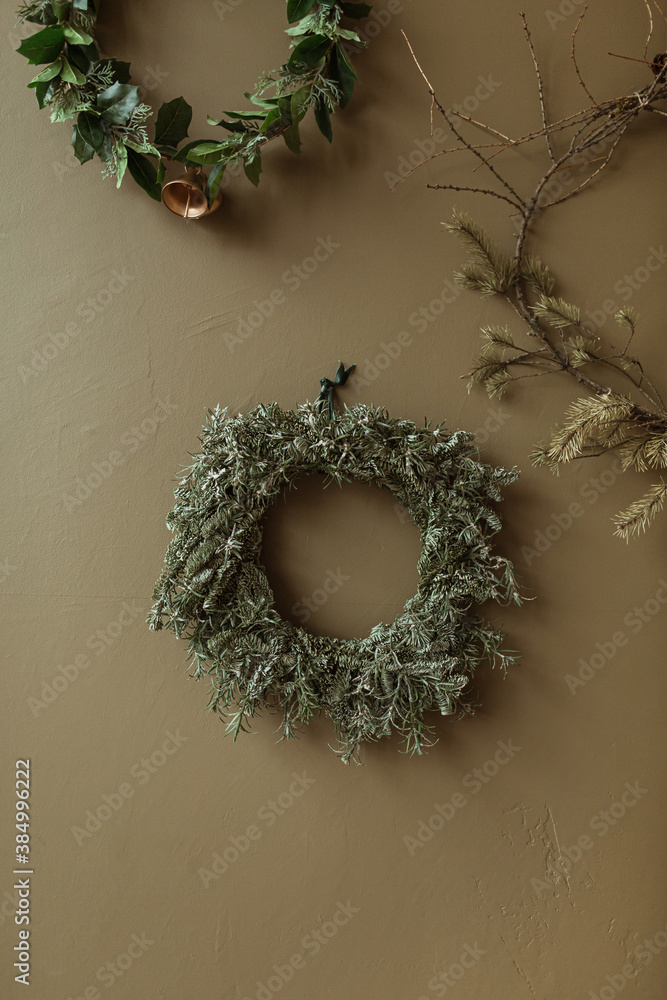 Round homemade wreath frames made of fir needles and branches on olive wall. Christmas / New Year celebration decorations. Round homemade wreath frames made of fir needles and branches on olive wall. Christmas / New Year celebration decorations.