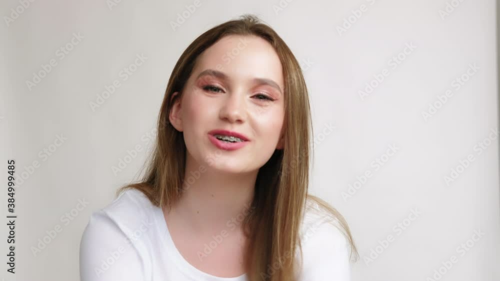 Love signal. Romantic message. Amused teen girl in white t-shirt blowing air kiss showing heart gesture isolated on light copy space background. Admiration support affection. Love signal. Romantic message. Amused teen girl in white t-shirt blowing air kiss showing heart gesture isolated on light copy space background. Admiration support affection.
