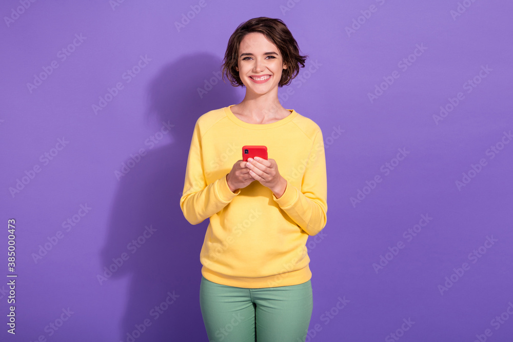 Photo of positive girl hold smartphone with social network posts isolated over violet color background Photo of positive girl hold smartphone with social network posts isolated over violet color background