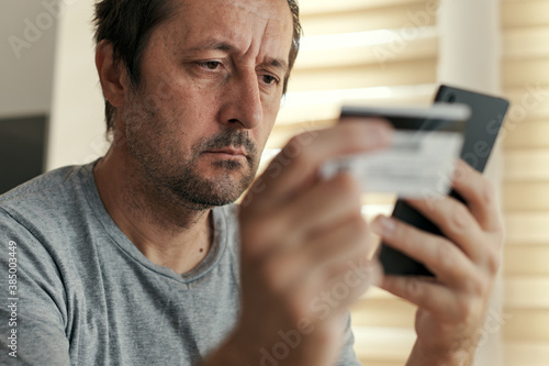 Man shopping online from home with mobile phone and credit card