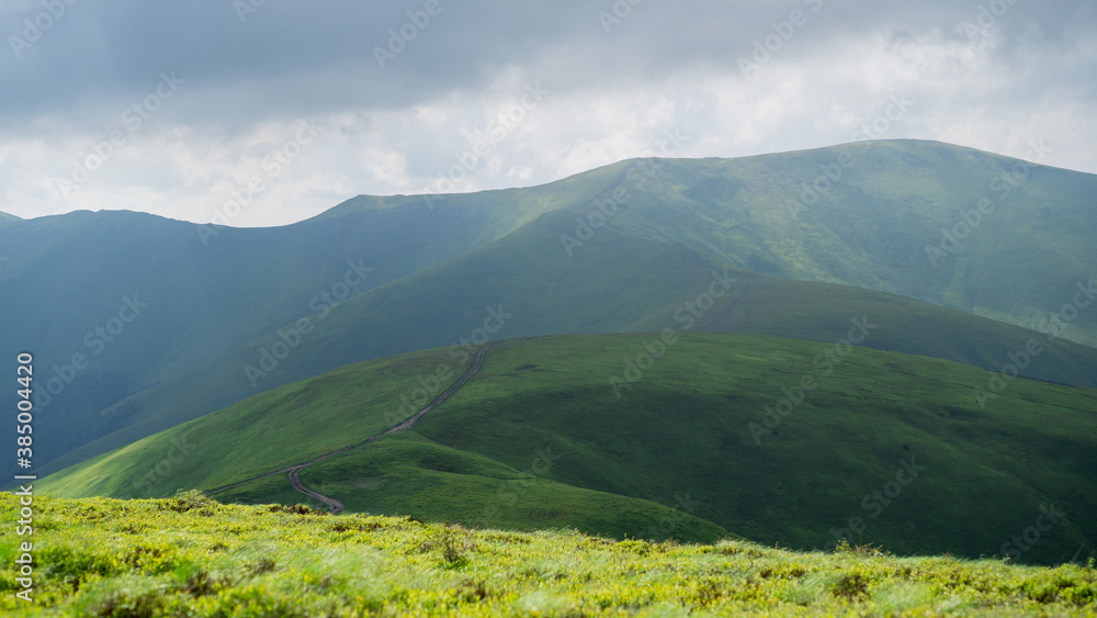 Cloudy sky over green mountains. Borzhavsky mountain range, Ukraine. Path in the mountain. Nature background
