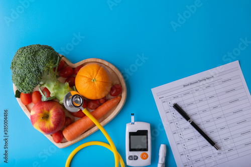 World diabetes day. National American diabetic awareness. Free Glucose Monitors on blue background. Yellow stethoscope check fruit on heart plate. Healthcare and medical concept