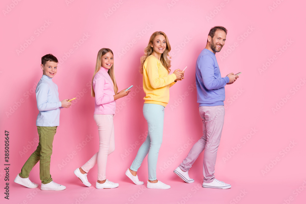 Obraz premium Full body profile side photo of dad mom small kids go with cell phone isolated over pink pastel color background