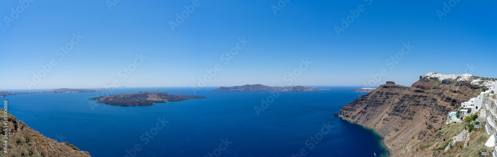 Beautiful panoramic view from Thira to caldera and volcano on a sunny day. Picturesque natural background with copy space for text. Santorini island, Cyclades, Greece, Europe.