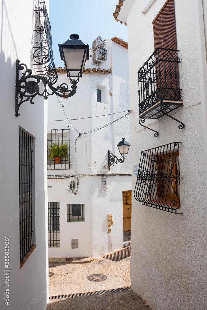 Beautiful narrow street in Altea, Costa Blanca, Valencian Community, Spain. Historical center. Vertical shot. White greek-like architecture. 