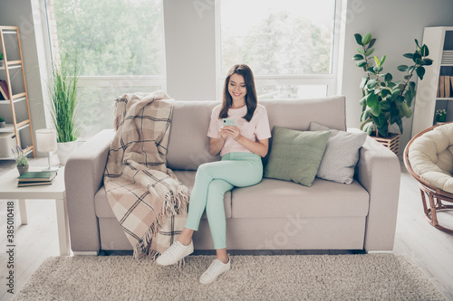 Photography Photo portrait of modest woman sitting on couch with crossed legs holding phone