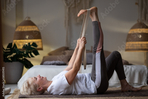 Принти на полотні woman working out, warming up using yogic belt, lying in yoga Supta Padangushtha