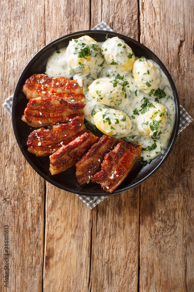 Stegt flæsk is a dish from Denmark consisting of fried pork belly and  generally served with potatoes and a white sauce with chopped parsley  Vertical top view from above Stock Photo