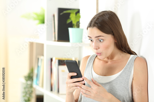 Surprised woman checks mobile phone content