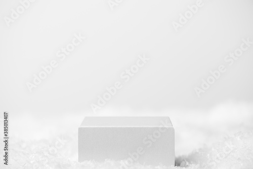 Podium geometric shape white on a white background. Winter scene, showcase with snow for product presentation. Minimalistic light pedestal for cosmetic. Copy space