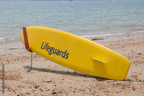 A surf board on a beach with the word lifeguards written on it