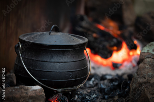 Cast iron pot cooking over red hot coles photo