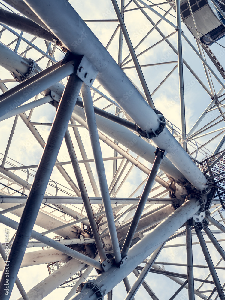 Gray or white metal ferris wheel with closed passenger cabins close-up in the amusement park