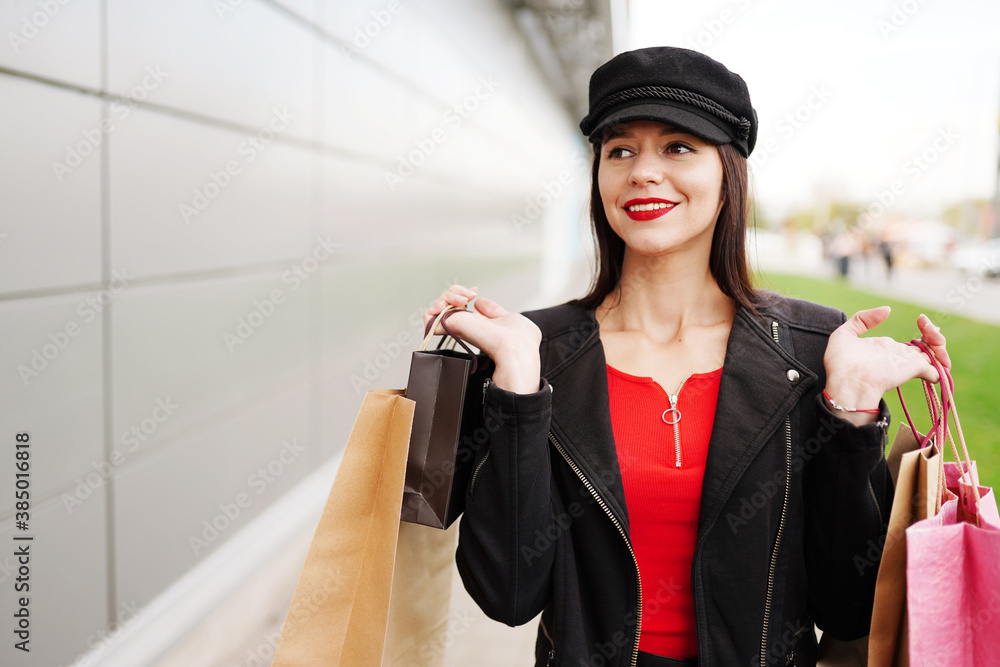 Smiling girl in black cloth with shopping bags outdoors