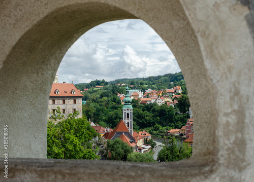 Beautiful rooftop view throw stone hole to historical center, church and castle in Cesky Krumlov, Czech republic.
